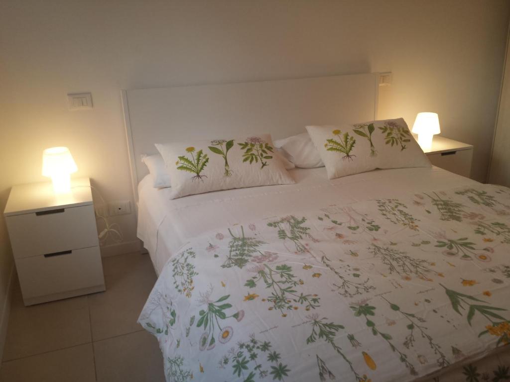 a bedroom with a white bed with pillows and two lamps at Mare e Monti Apartment in Marina di Carrara