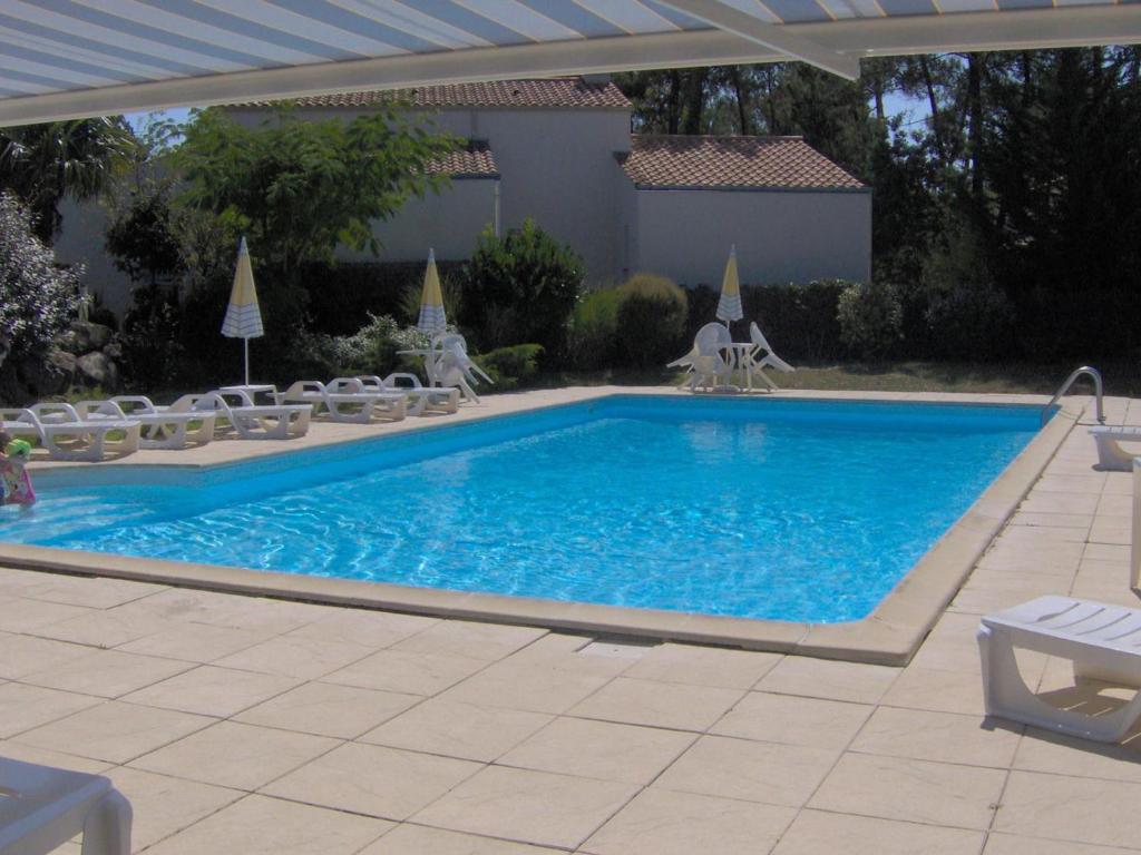 une grande piscine avec des chaises et une table dans l'établissement Appartement agréable avec terrasse, piscine et à 600m de la plage, La Tranche-sur-Mer - FR-1-194-107, à La Tranche-sur-Mer