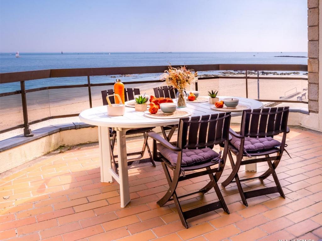 einen Tisch mit Obst und Gemüse auf einem Balkon mit Blick auf den Strand in der Unterkunft Larmor-Plage T4 Spacieux avec Terrasse, Ascenseur et Parking face à la Mer - FR-1-349-124 in Larmor-Plage