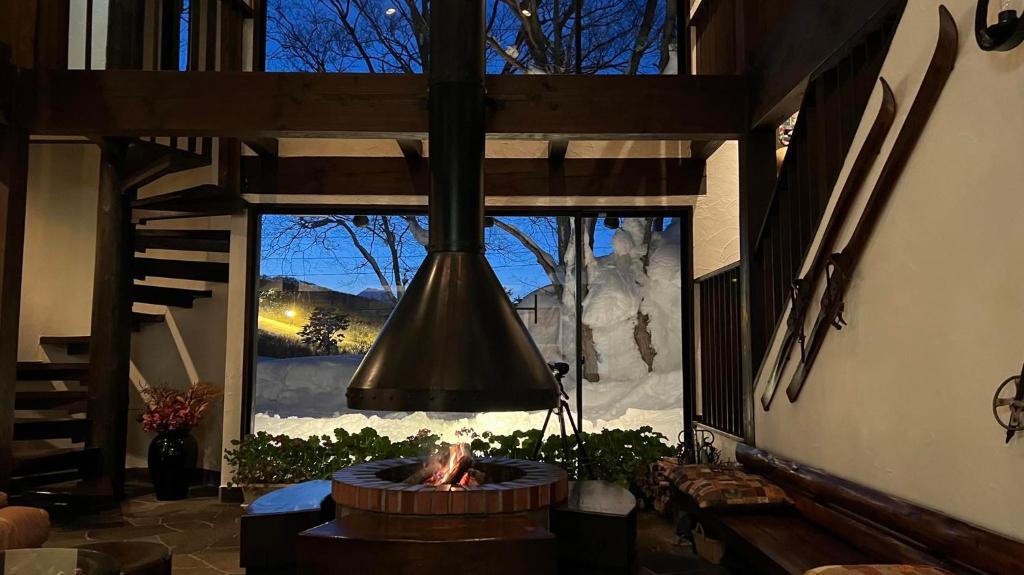 a fireplace in a living room with a large window at Alp Bach Madarao in Iiyama