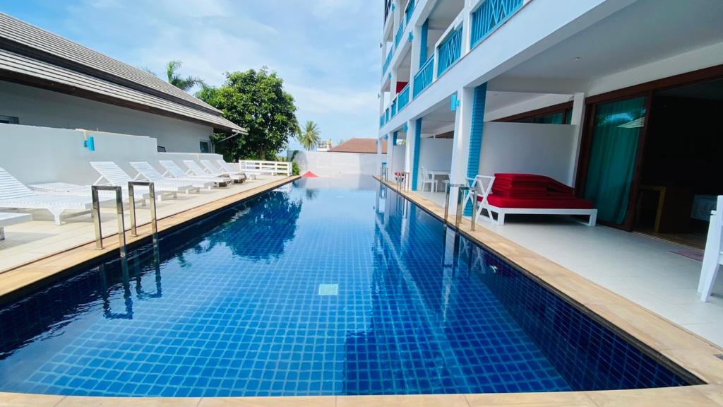 a swimming pool with chairs next to a building at Samui Mekkala Resort in Choeng Mon Beach