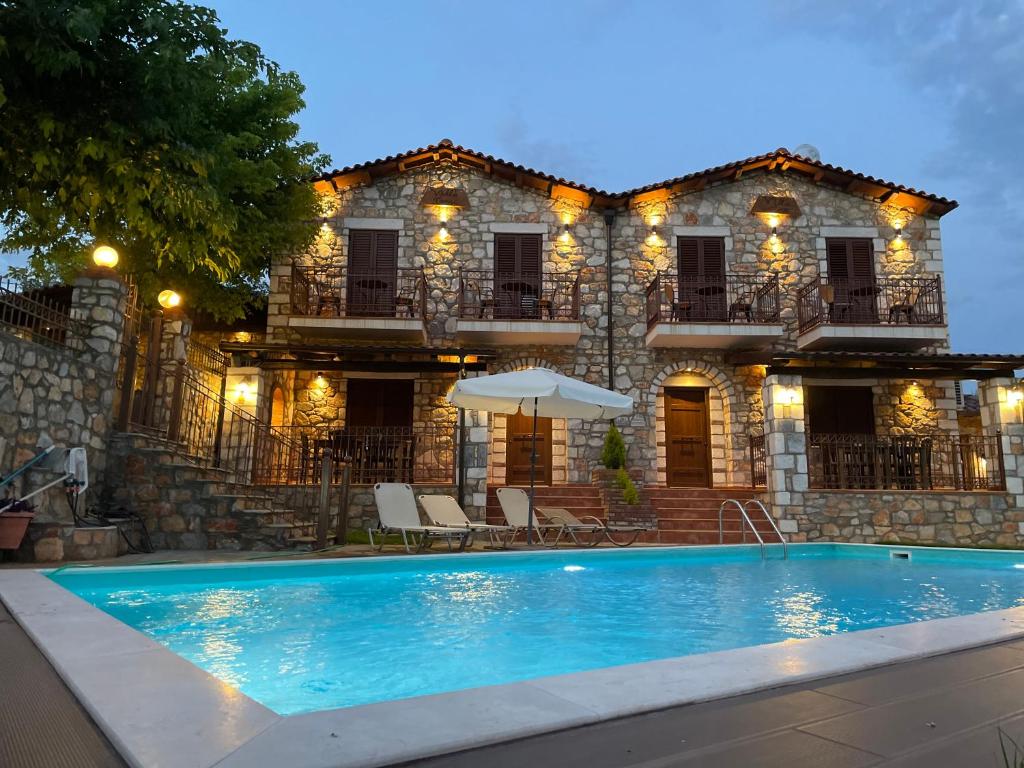 a house with a swimming pool in front of a building at Petrines Villes Avramilias in Avramiliá
