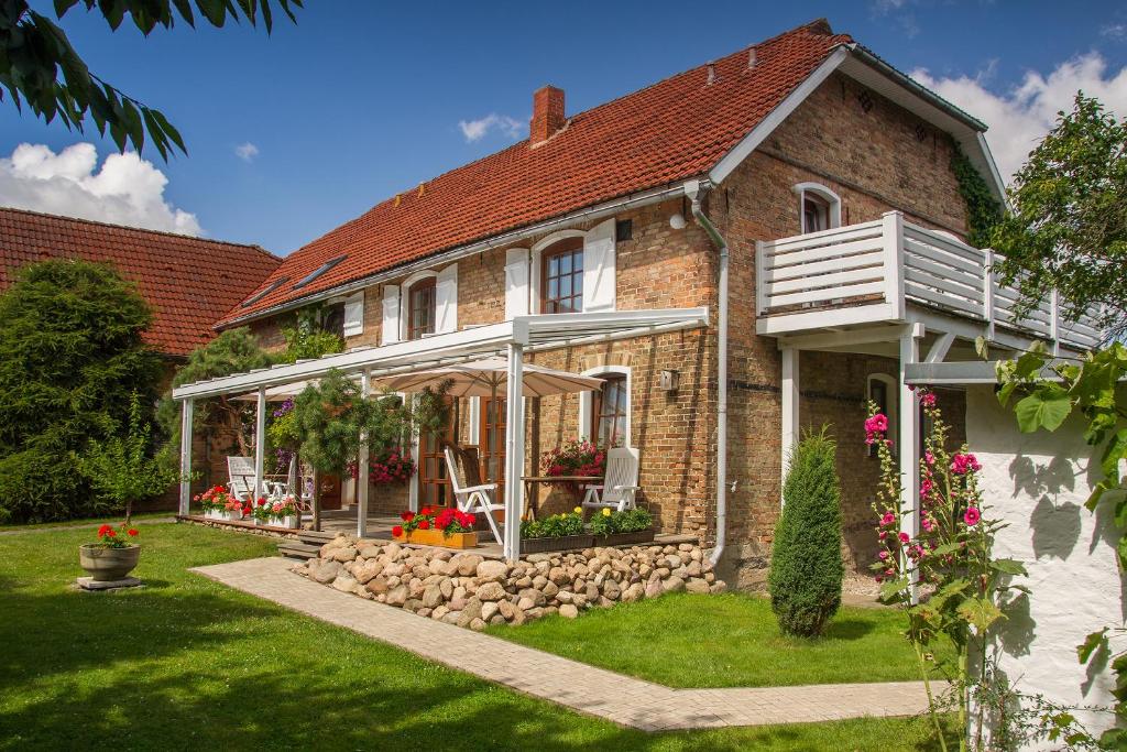 una casa in mattoni con portico con sedie e fiori di Pension zur Scheune a Plau am See