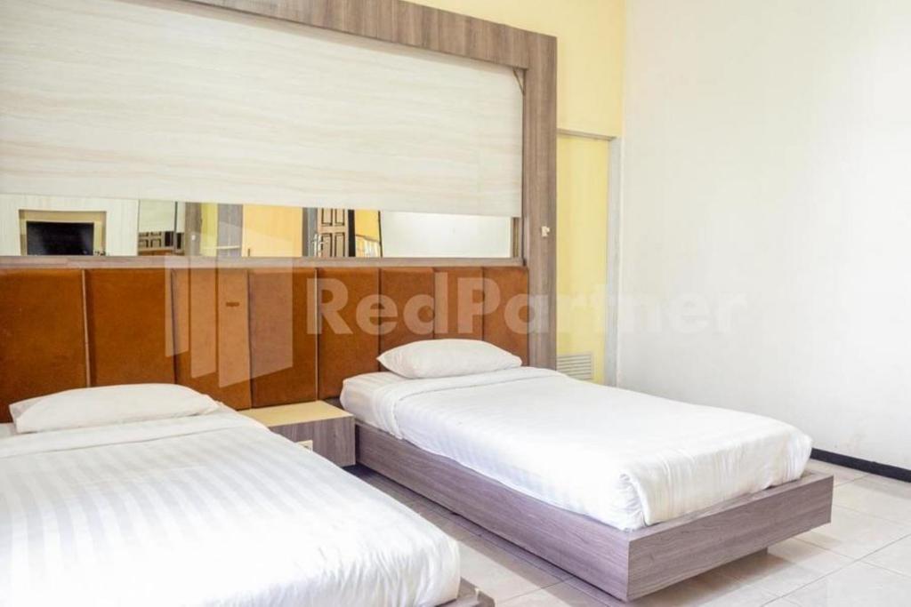 2 camas en una habitación con espejo en My Hommy Homestay Mitra RedDoorz, en Surabaya