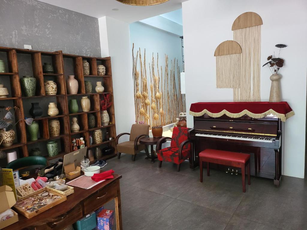a living room with a piano and shelves of vases at 5 Elements Hotel in Quy Nhon