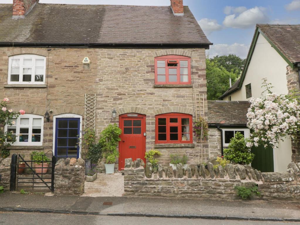 a brick house with a red door and red windows at Stone Cottage in Hereford