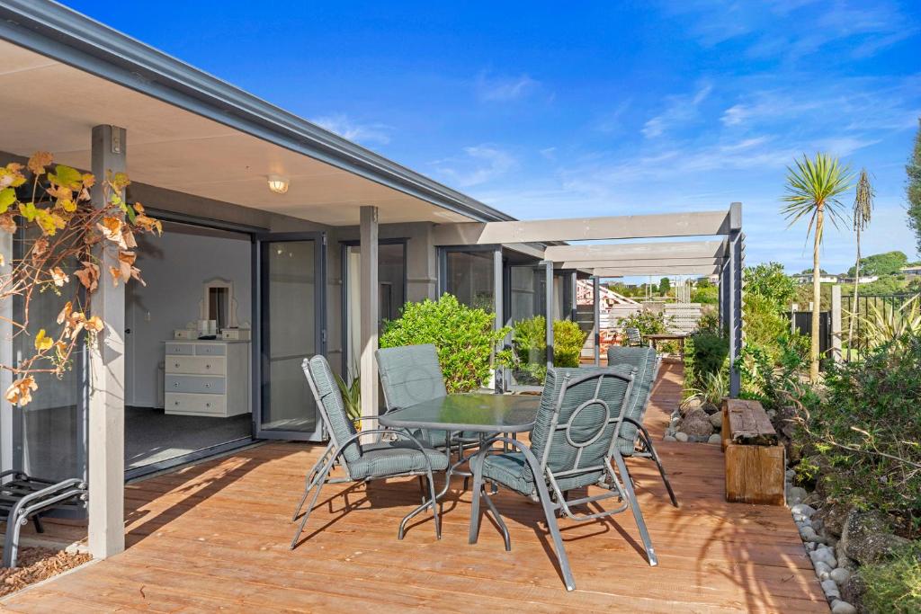 a patio with a table and chairs on a deck at Ruakaka River Retreat - Ruakaka Holiday Home in Ruakaka