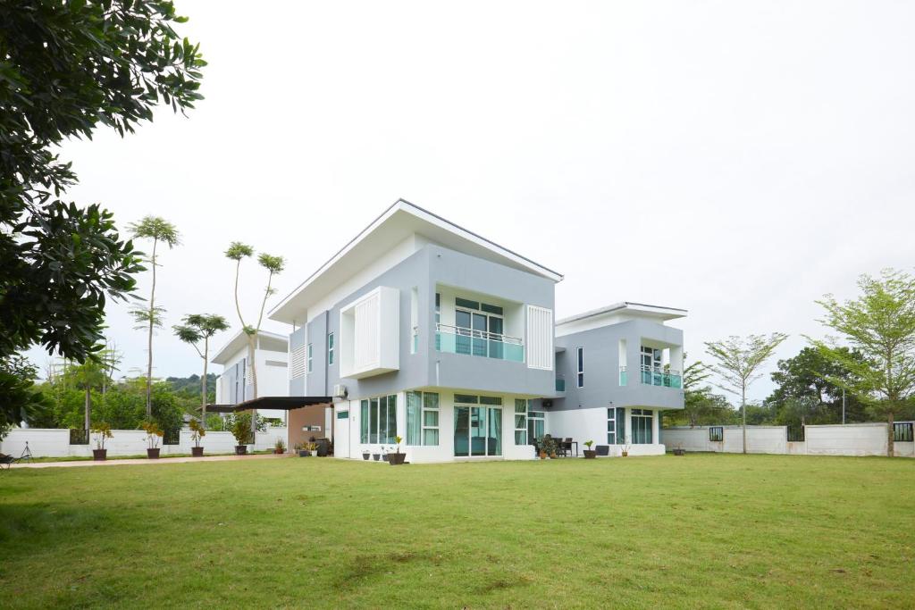una gran casa blanca con un gran patio en Desaru Arcadia Villa By Convergence, en Bandar Penawar