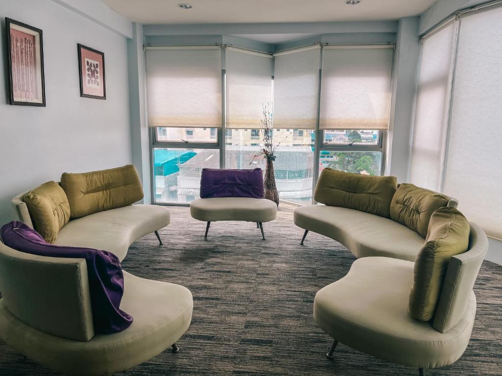 a waiting room with couches and chairs and windows at Neo Hatyai Hotel in Hat Yai