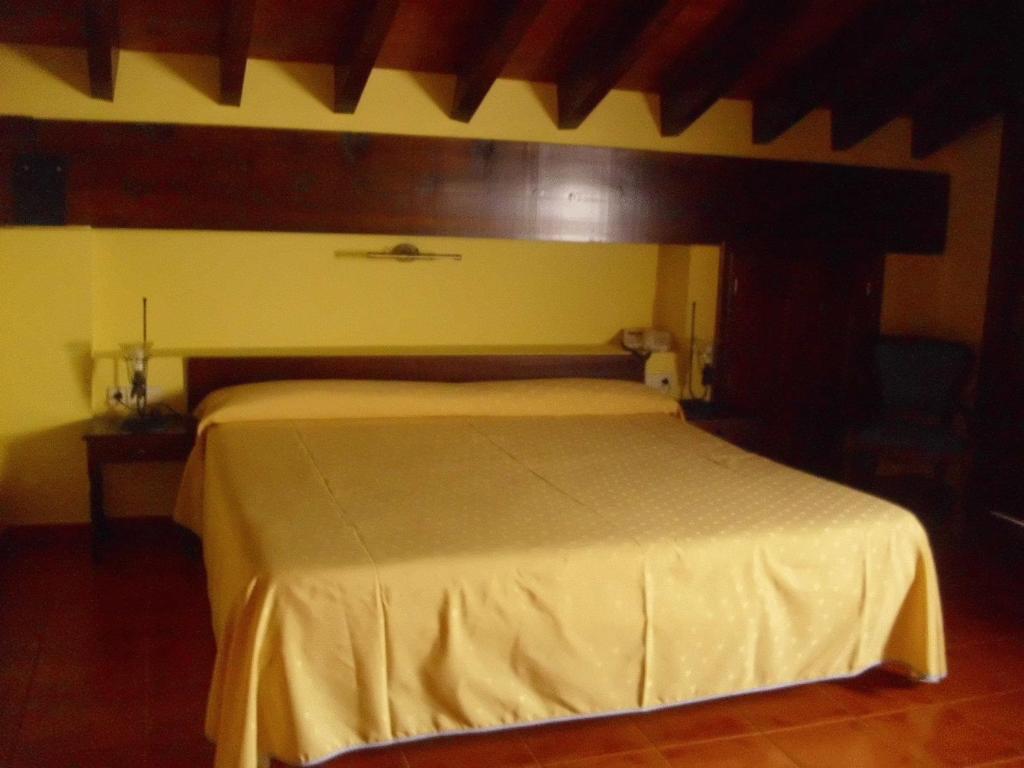 a bedroom with a large bed with a yellow wall at Hostal La Mancha in Tarazona de la Mancha