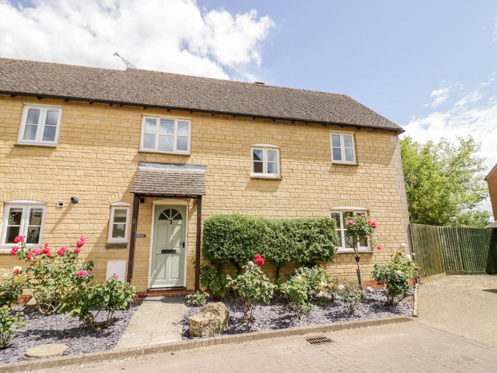 une maison en briques avec des fleurs devant elle dans l'établissement Rosemead, à Moreton-in-Marsh