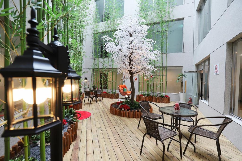 dziedziniec ze stołami i krzesłami oraz drzewem w budynku w obiekcie Hotel the maru w mieście Pjongczang