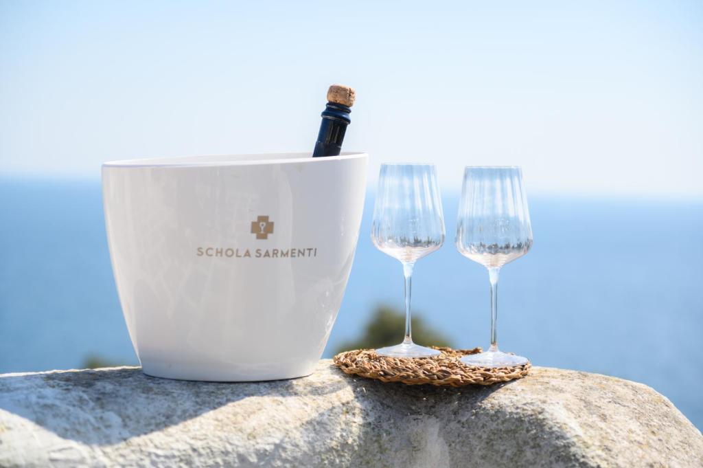 Dois copos de vinho e um balde com uma garrafa de vinho. em Salento incantevole alloggio fronte mare em Marittima