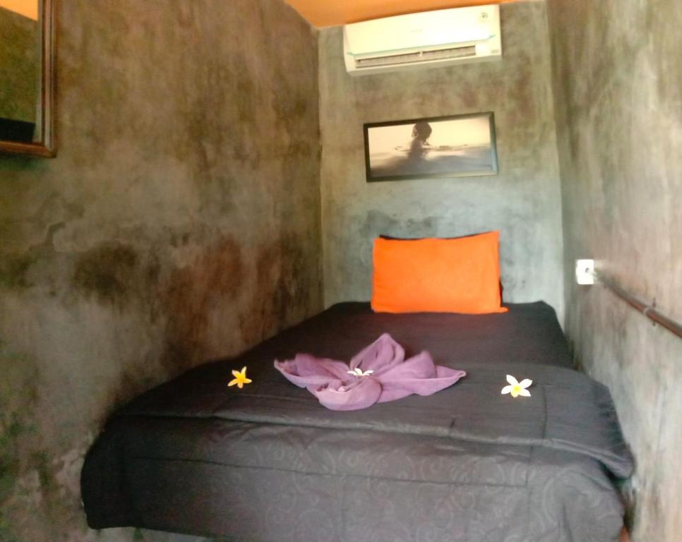 a bedroom with a bed with purple flowers on it at Keramas Surf Hostel in Keramas