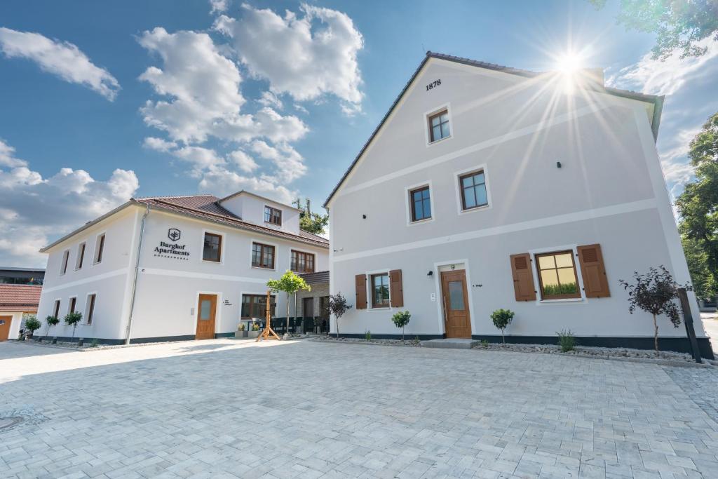 un gran edificio blanco con el sol en el cielo en Burghof Apartments Hoyerswerda en Hoyerswerda