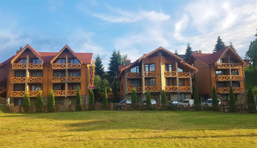 a large wooden house with cars parked in front of it at Karpatski Zori Hotel in Bukovel