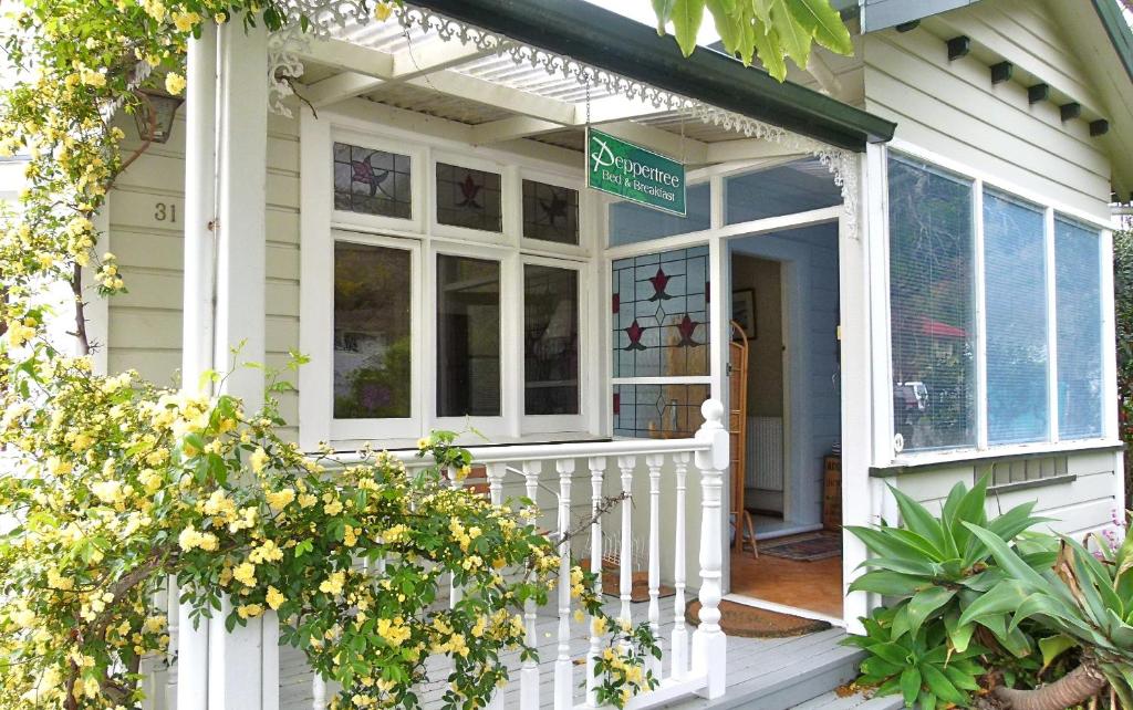 Una casa blanca con un porche con un cartel. en Peppertree Bed & Breakfast, en Nelson