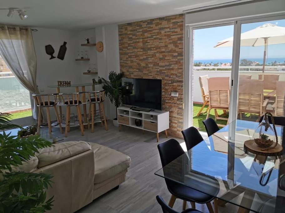 a living room with a couch and a table with a television at Ático 4 dormitorios cerca de la playa con gran terraza y 2 parkings in Roquetas de Mar