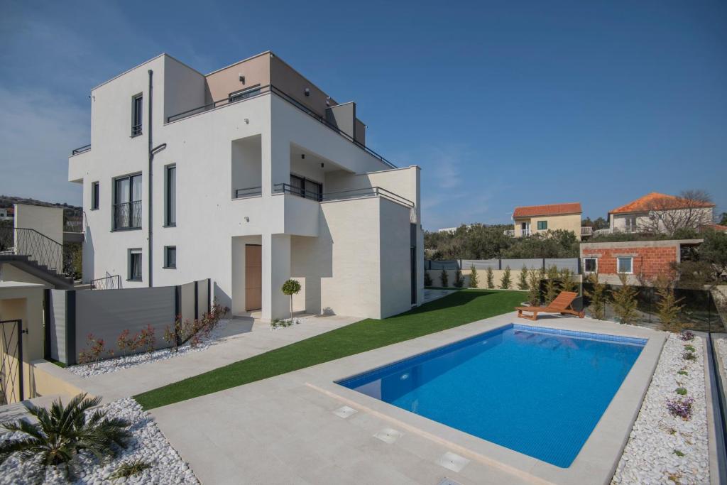 a villa with a swimming pool in front of a house at Villa Magna luxury apartments in Murter