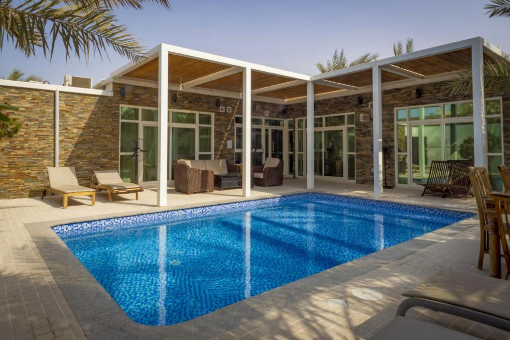 a swimming pool in front of a house at Dar 66 Pool Chalets with Jacuzzi in Ras al Khaimah