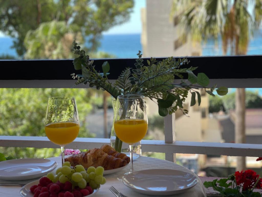 dos vasos de zumo de naranja y uvas en una mesa en STUDIO SECOND LINE OF THE BEACH CENTER SEA VIEW, en Marbella