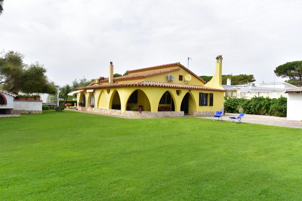 una casa amarilla con un césped verde delante de ella en villa Letizia en Pula