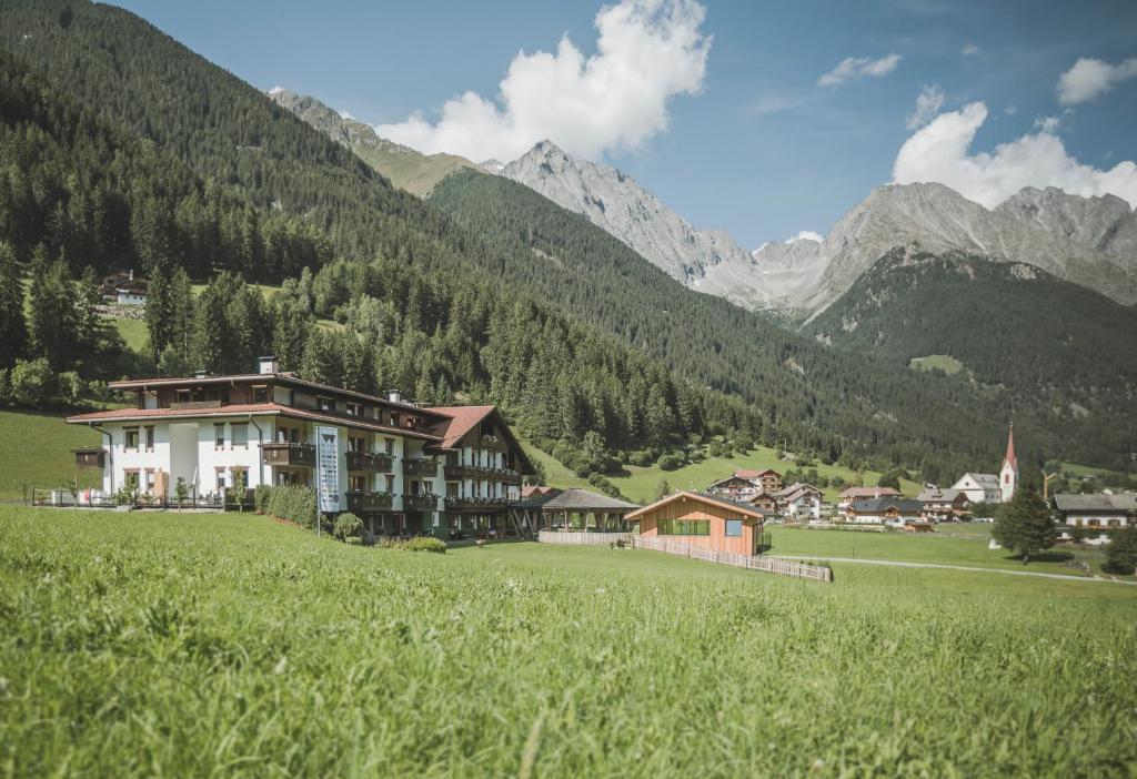 a building in a field with mountains in the background at Vierbrunnenhof in Anterselva di Mezzo