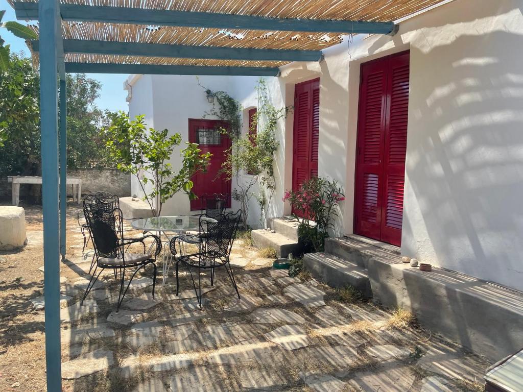 eine Terrasse mit Stühlen, einem Tisch und roten Türen in der Unterkunft Fishermans House in Khlóï