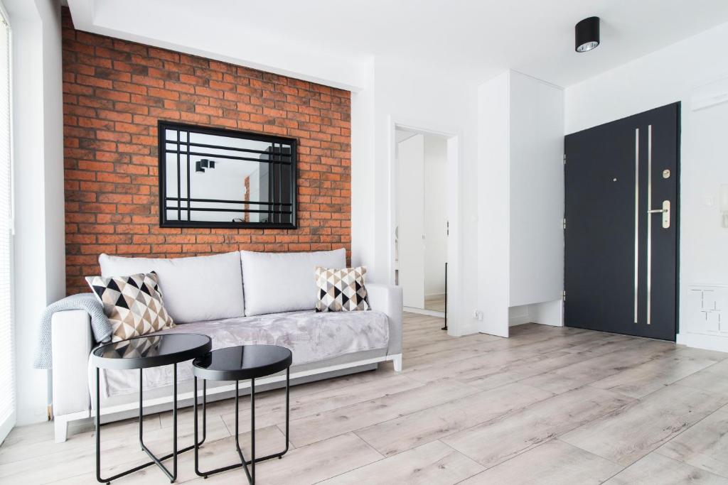 a living room with a couch and a brick wall at Apartment City Centre Netflix- GreenPark - River in Olsztyn