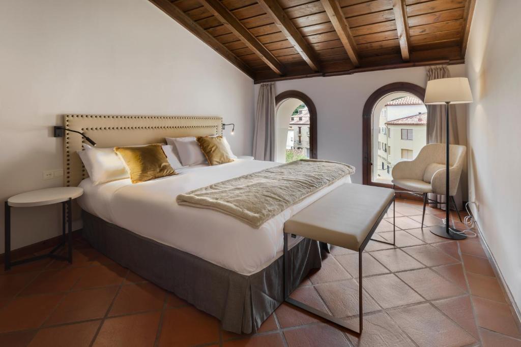 een slaapkamer met een bed, een stoel en een raam bij Hotel Restaurante & Spa Palacio Matutano-Daudén in La Iglesuela del Cid