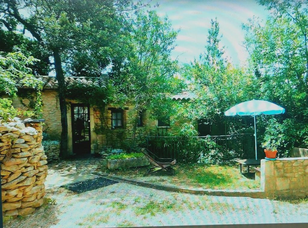 um quintal com uma casa com um guarda-chuva em Le Mazet em Souvignargues