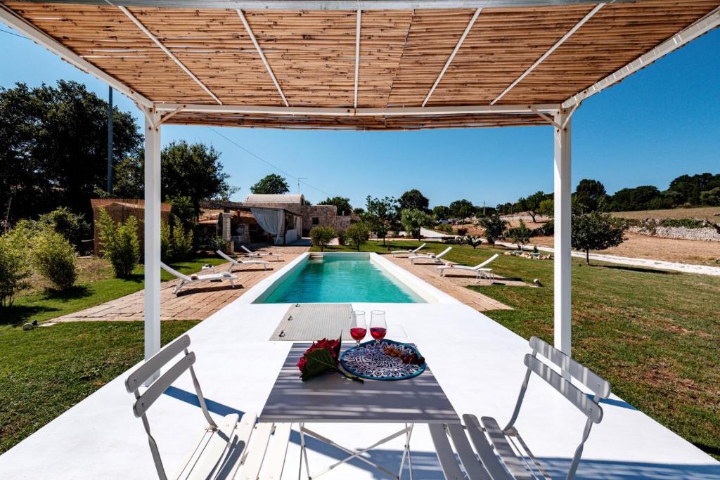 a patio with a table and chairs next to a swimming pool at HelloApulia - Typical Cottage Lamia delle Murge in Ostuni