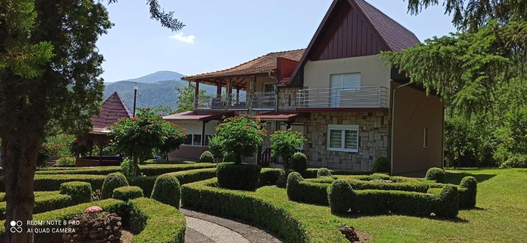 uma casa com sebes bem paisagísticas em frente em Guest House Vila Aleksa-apartman em Bogutovac