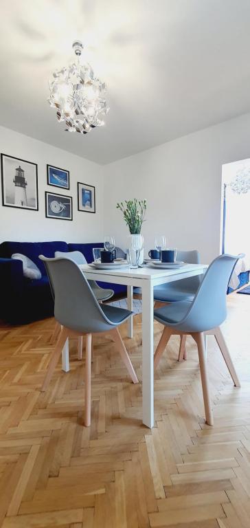 a dining room with a white table and blue chairs at Villa Łeba II - Loft Apartments in Łeba