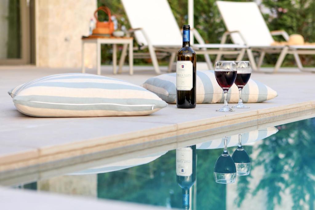 two glasses of wine sitting on a table next to a swimming pool at My Mediterranean Corfu Luxury Villa with Private Swimming Pool in Kontokali