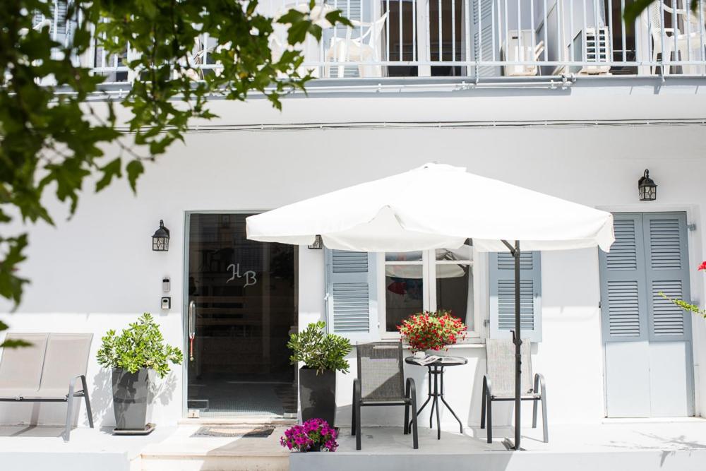a white building with a table and an umbrella at HB Hotel Benitsa in Benitses