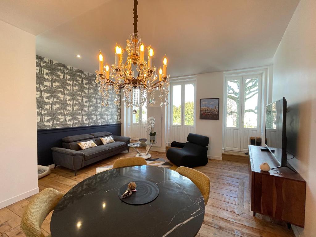 een woonkamer met een tafel en een kroonluchter bij Appartement de grand standing in Saintes