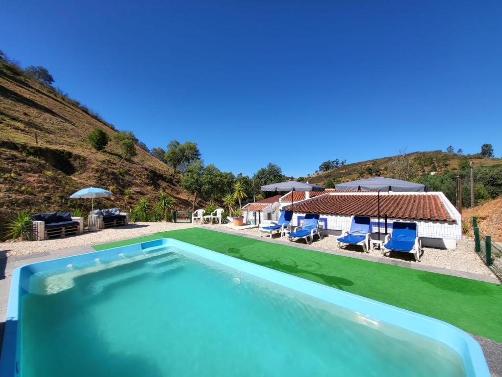 a swimming pool with chairs and a house at Casa Rochinha in Portimão