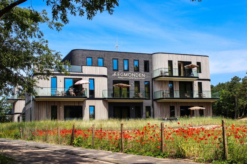 a building with red flowers in front of it at De Egmonden in Egmond aan Zee