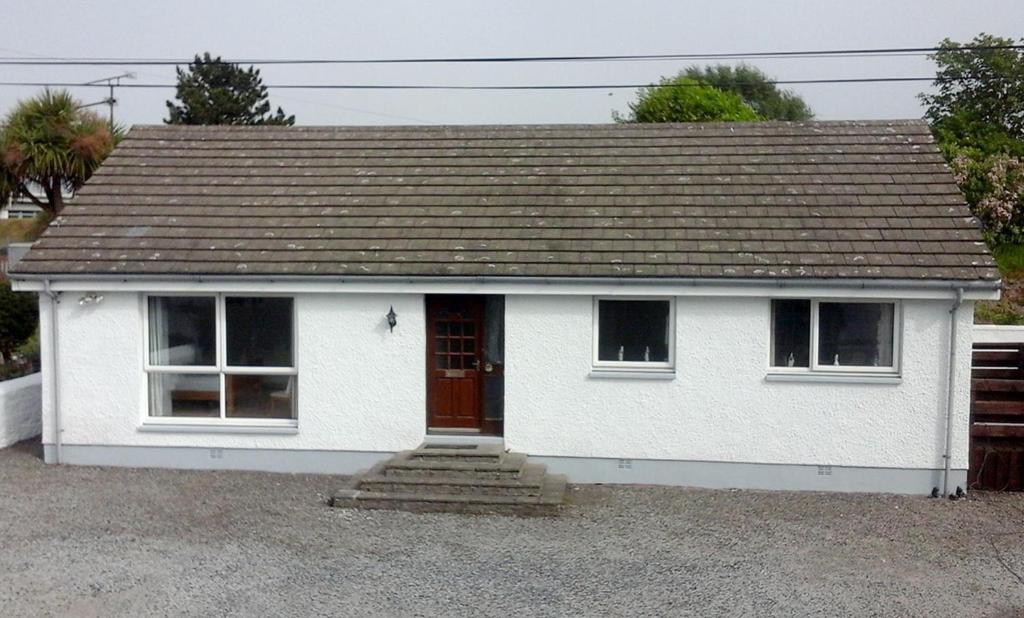 a small white house with a brown roof at Lovely 3 Bedroom Bungalow Located in Drummore in Drummore