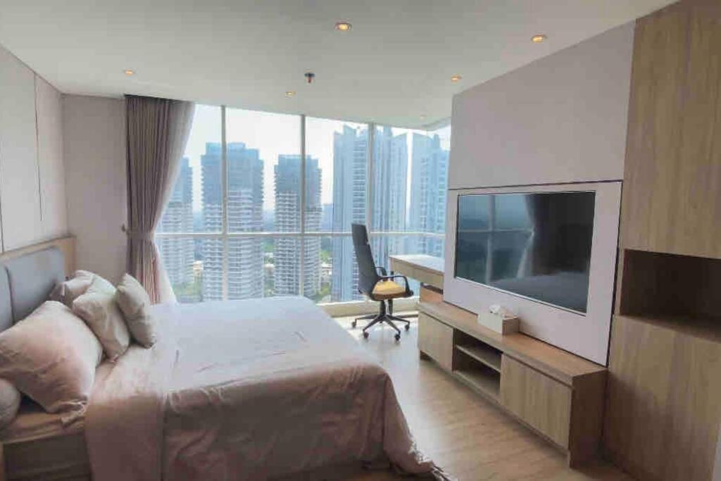 a hotel room with a large bed and a television at 3BR apt Springhill Terrace, golf view in Jakarta