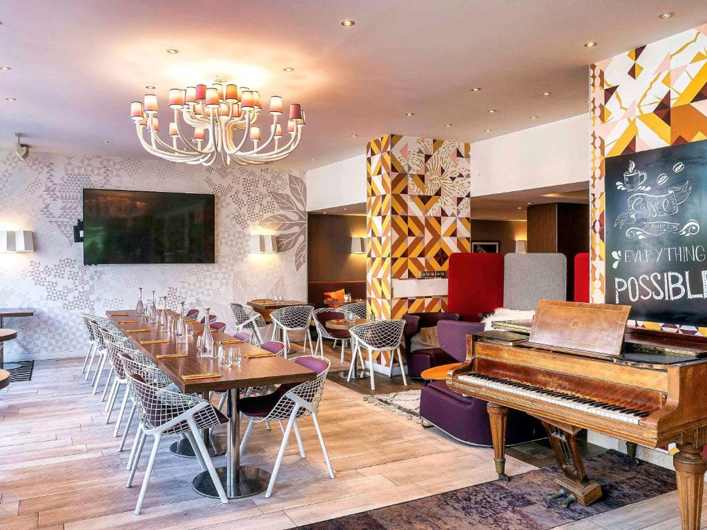 restauracja z pianinem, stołami i krzesłami w obiekcie Mercure Paris Montmartre Sacré Coeur w Paryżu