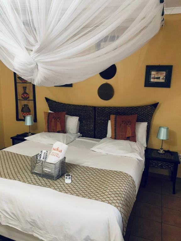 a bedroom with two beds with white drapes at Xisaka Guest House in Giyani