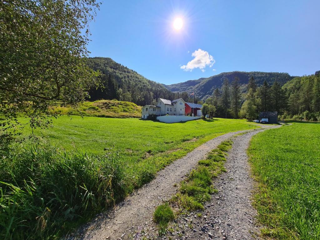 eine unbefestigte Straße, die zu einem Haus auf einem Feld führt in der Unterkunft Jondal in Jondal