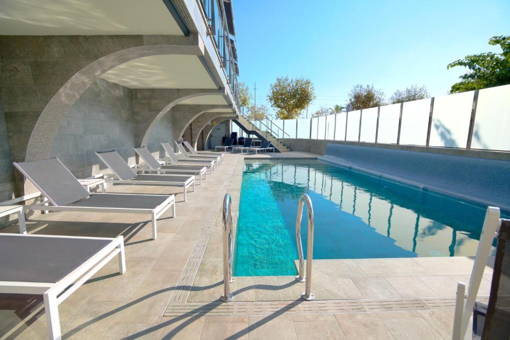 a swimming pool with lounge chairs next to a building at Hotel Internacional in Calella