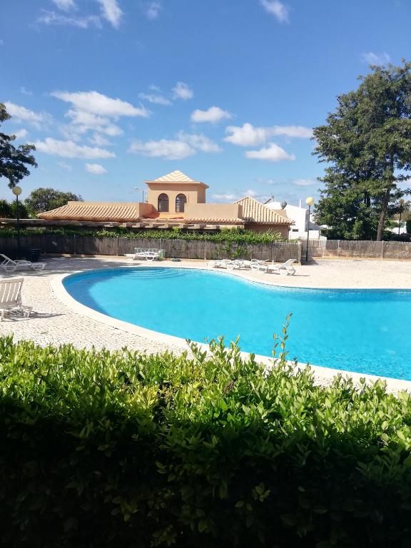 a blue swimming pool with a building in the background at Villa V2 U in Olhos de Água