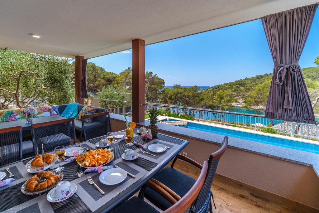 Villa Karmelota في ميلنا: غرفة طعام مع طاولة وإطلالة على المسبح