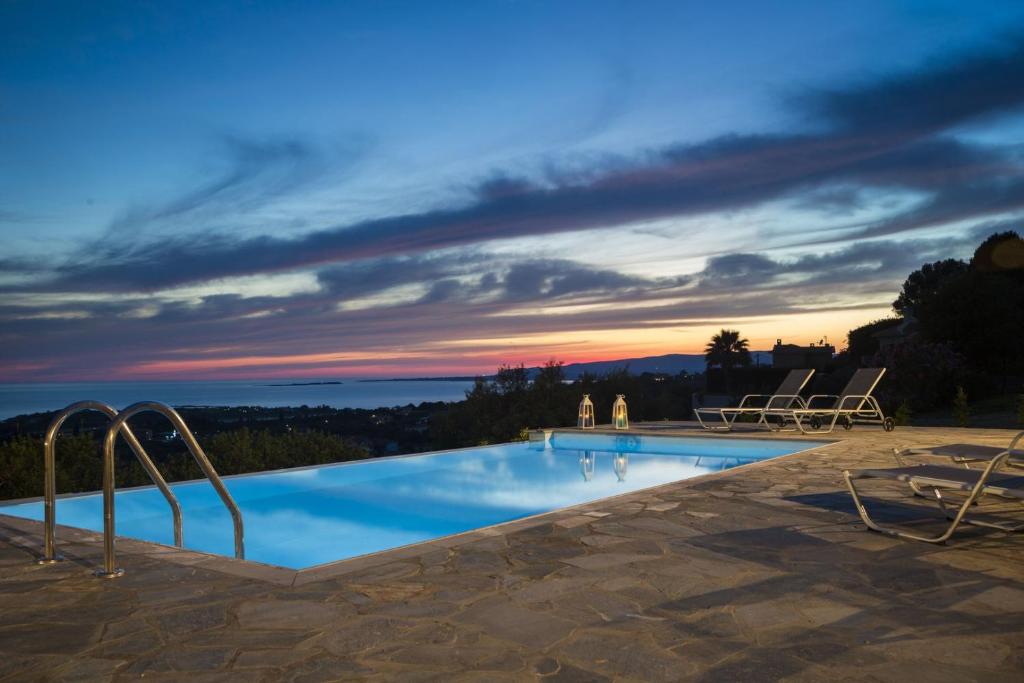 a swimming pool with a sunset in the background at Villa Elaia in Svoronata