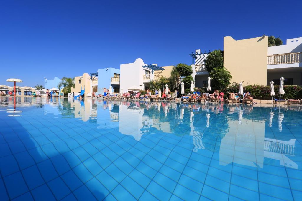 a swimming pool with people sitting on chairs in the water at Eleni Holiday Village in Paphos