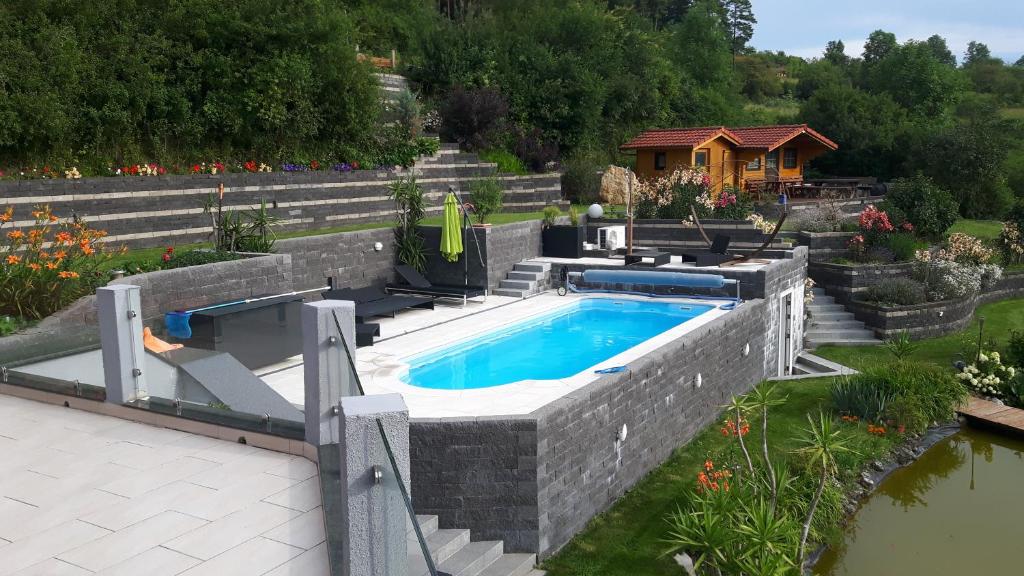 a swimming pool in a garden with a house at All Senses Ferienwohnung in Hirschbach